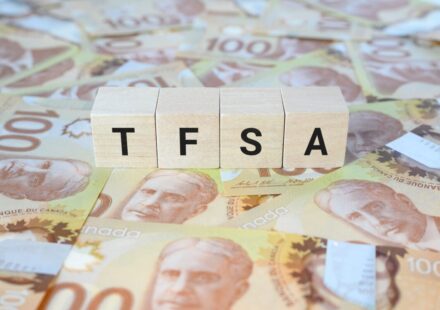 TFSA (Tax-Free Savings Account) on wooden blocks and Canadian one hundred dollar bills.