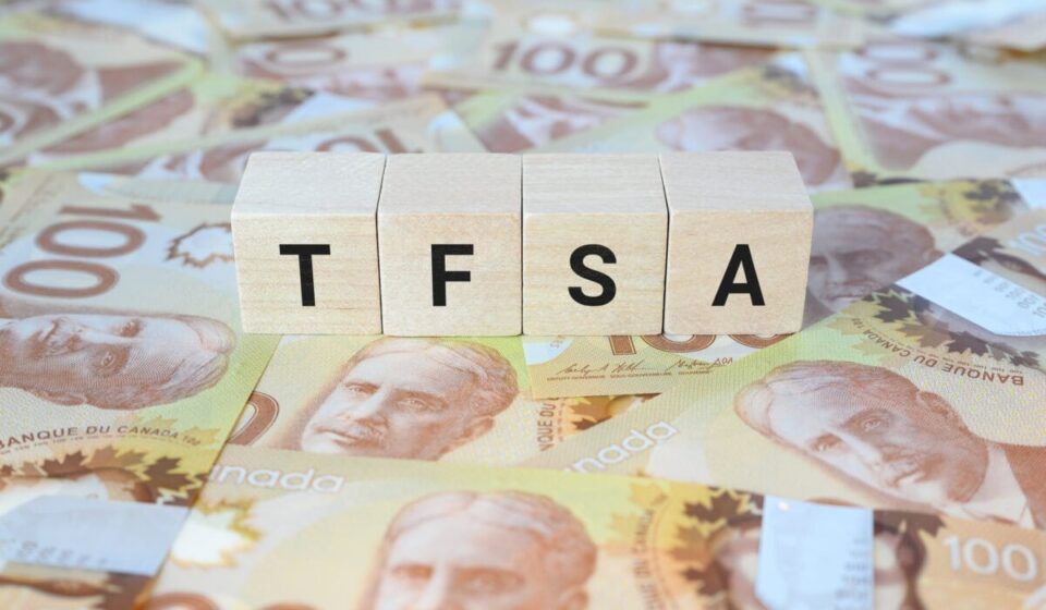 TFSA (Tax-Free Savings Account) on wooden blocks and Canadian one hundred dollar bills.