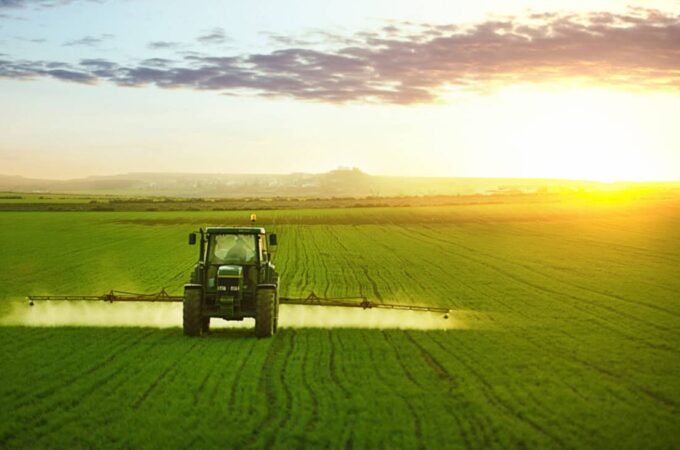 Tractor spraying a field of wheat with fertilizer
