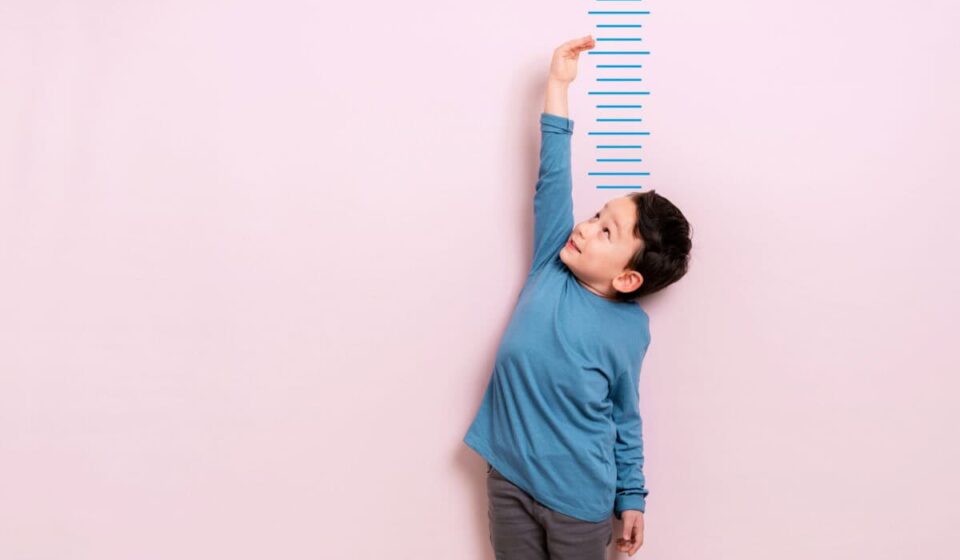 Child measures his height on wall. He is growing taller.