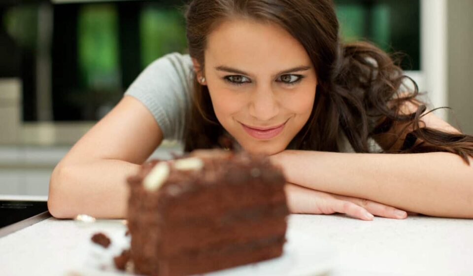 woman stares at chocolate layer cake