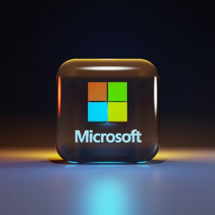 A glossy glass cube with the Microsoft logo on a dark surface