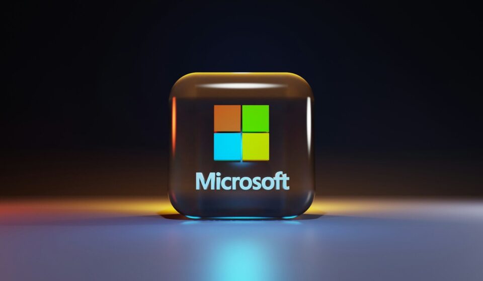 A glossy glass cube with the Microsoft logo on a dark surface