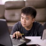 Opening Your First Investing Account in Canada: What to Know Before You Click “Apply” Young adult concentrates on laptop screen